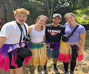 Rachel and friends in traditional grass skirts at an event