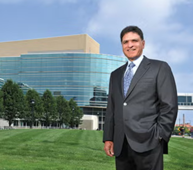 Photo of Monte Ahuja in front of the Monte Ahuja College of Business